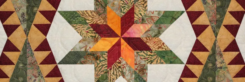 A close up of a quilt featuring a star shape made up of white, green, yellow and red fabric.