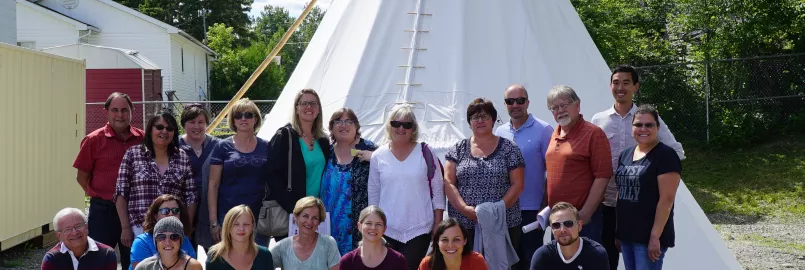 A group of people standing in front of a teepee