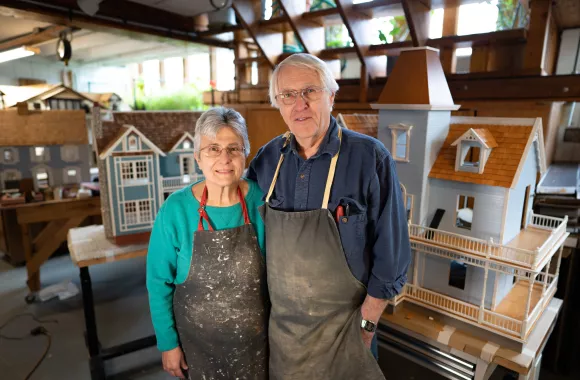 A man and woman standing in front of a room full of dollhouses
